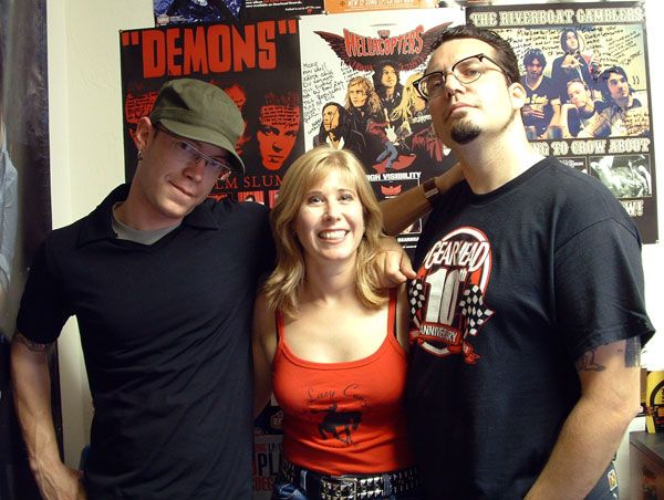 Mike LaVella, Michelle Haunold, and Joseph Lorenzo Hall standing in front of music posters.